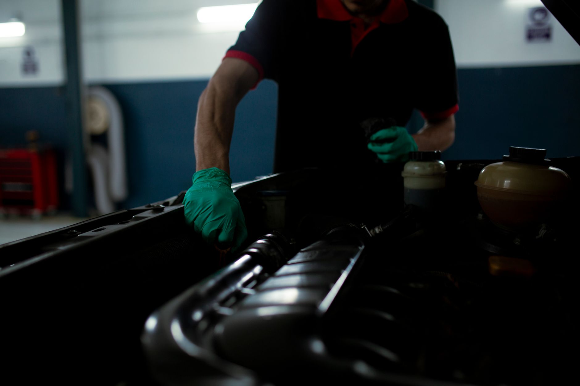 A mechanic in gloves inspecting a car engine bay