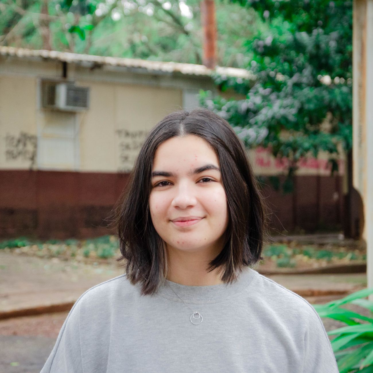 A woman with short dark hair smiling in a natural outdoor portrait