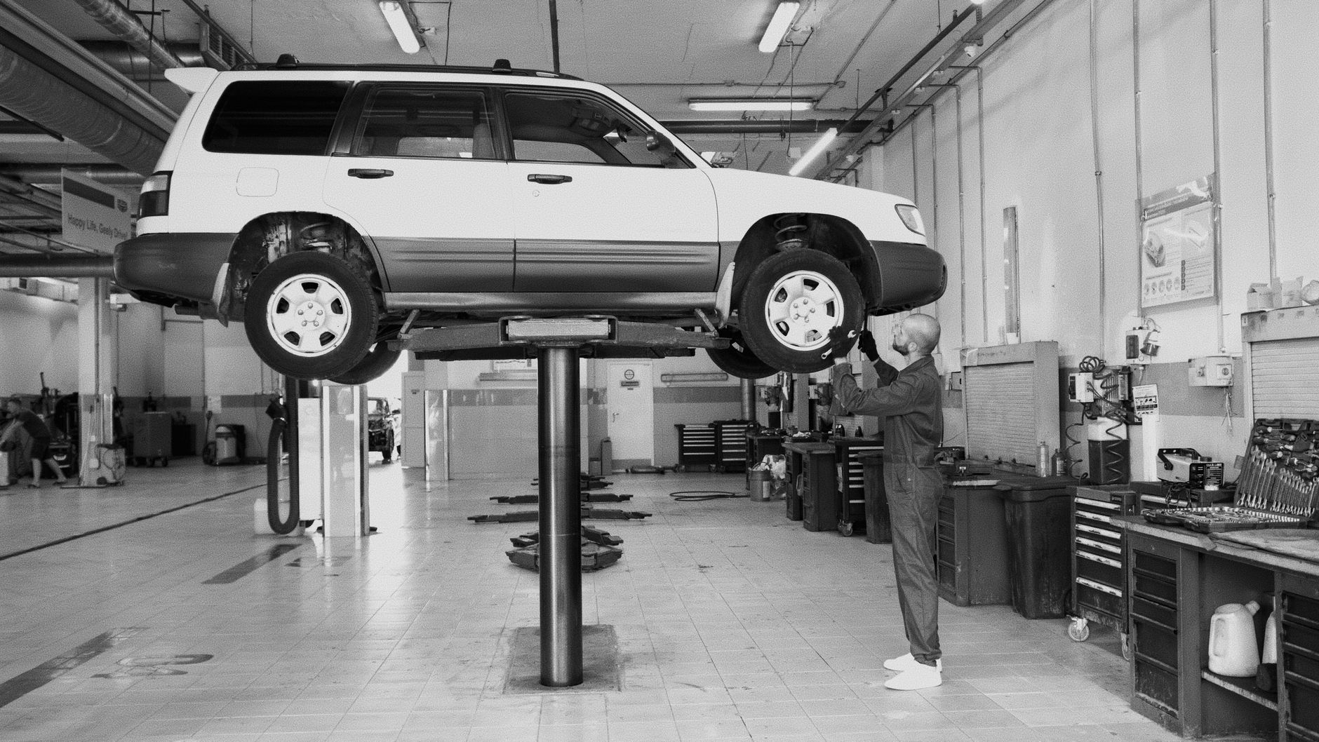 A mechanic examining a car raised on a lift in an auto repair shop